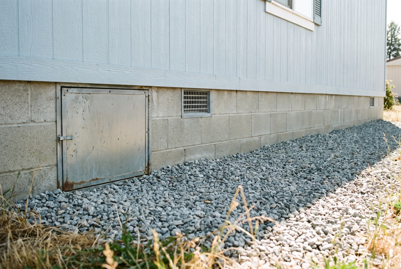 A manufactured home on a block perimeter foundation with an access door and vent